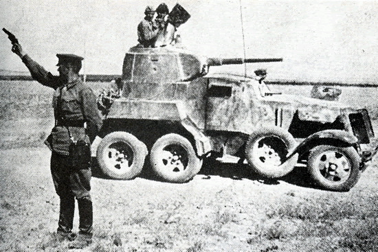 A Soviet officer wields a signal pistol next to a BA-10M