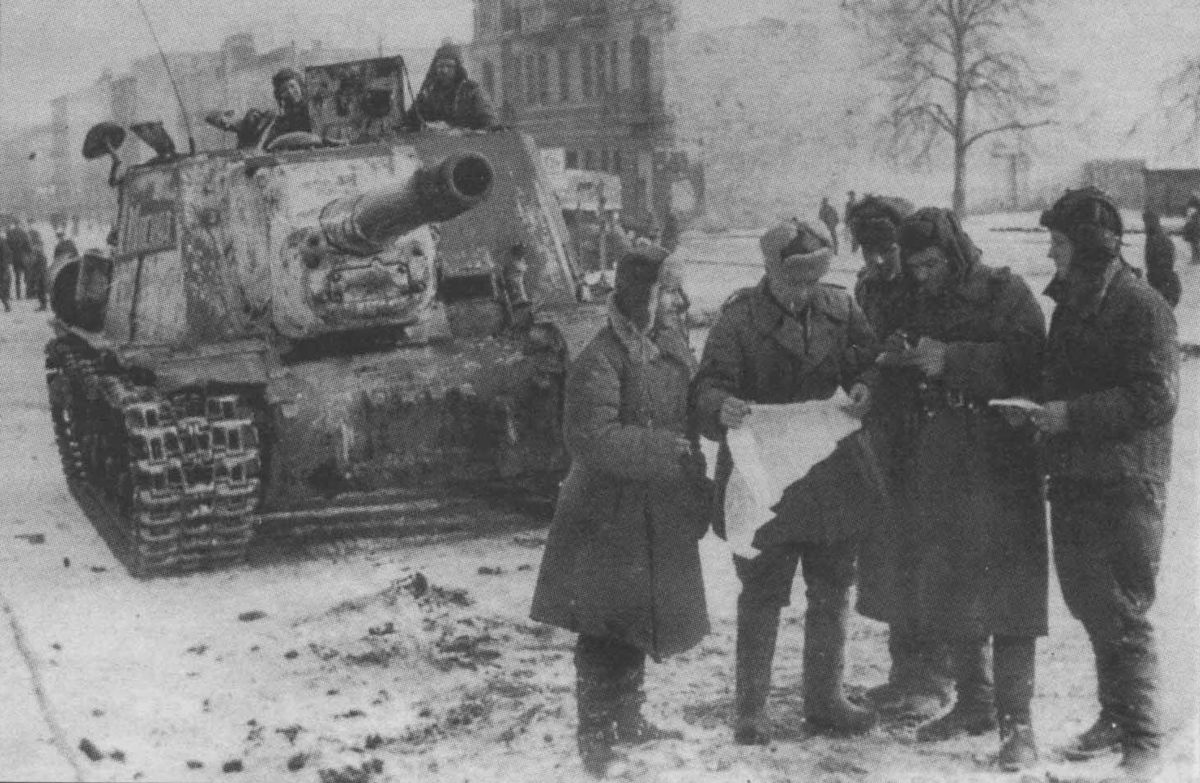 The commander of an ISU-152 and other officers consult a map during WWII.